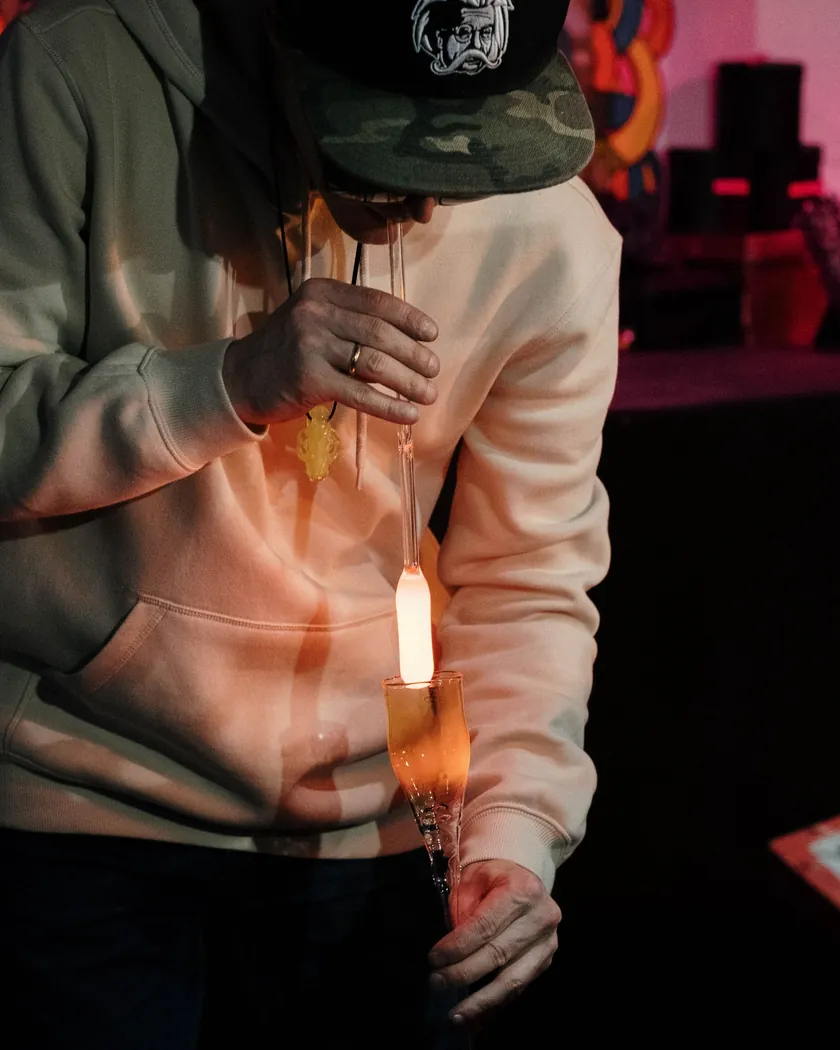 Detalle de una caña de soplar con vidrio incandescente durante el formado en un taller en penumbra